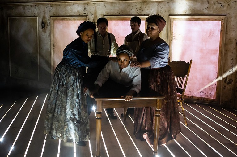 Two African American women hold another African American on a table