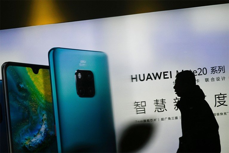 A man in dark profile walks past Huawei advertising outside a store in Beijing on January 29, 2019.
