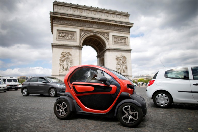 A Twizy electric car drives past the Arc de Triomphe in Paris