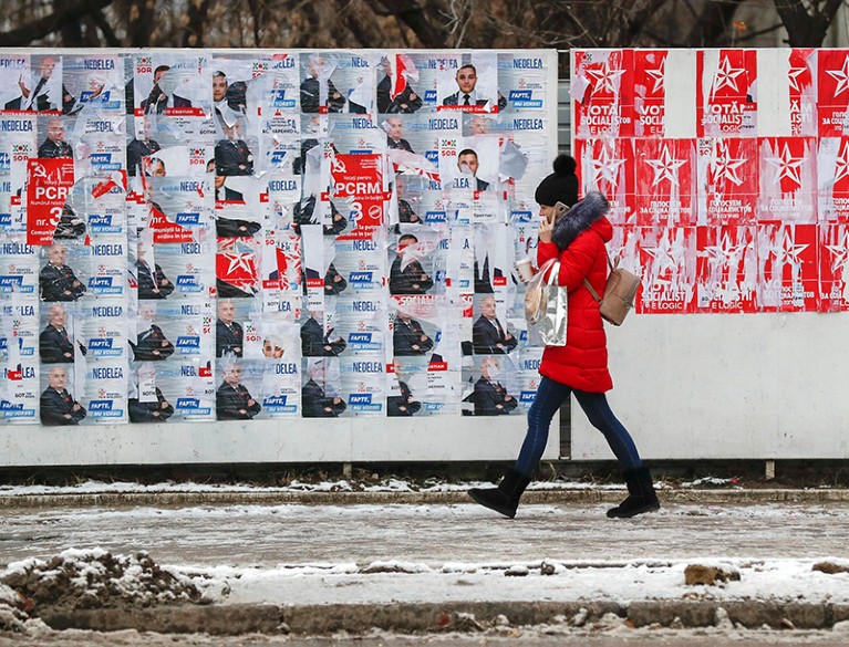 A woman walks past a panel with election campaign posters in downtown Chisinau, Moldova.