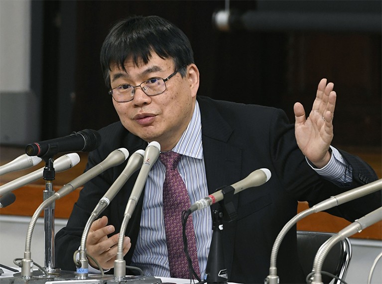 Keio University Professor Hideyuki Okano speaks into multiple microphones during a press conference on ips cell treatment