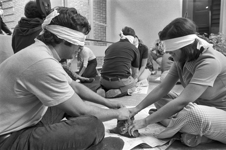 Black and white photo of participants in behavioural science experiment blindfolded and playing with clay
