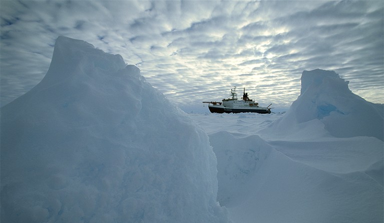 Icebreaker ship Polarstern in frozen sea ice with a dramatic sky overhead, Weddel Sea, Antarctica.