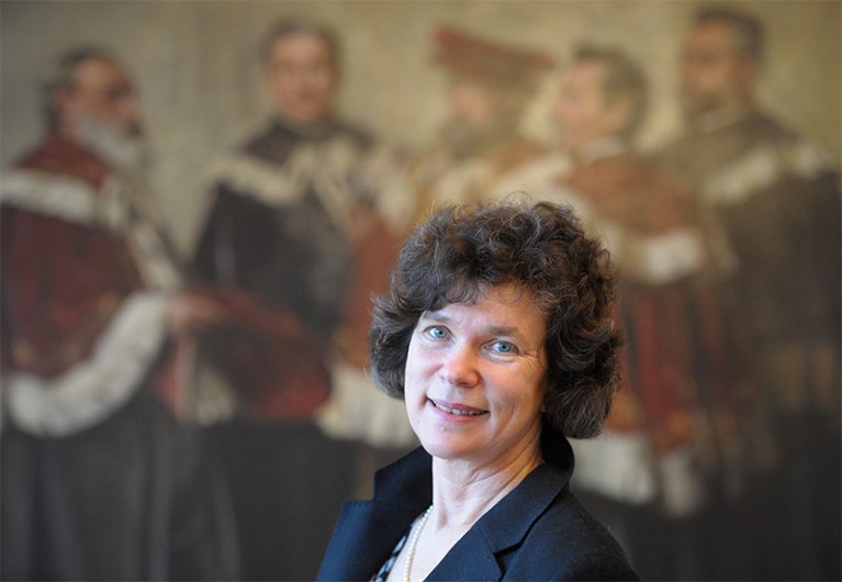 Beate Schücking standing in front of a painting of former university leaders.