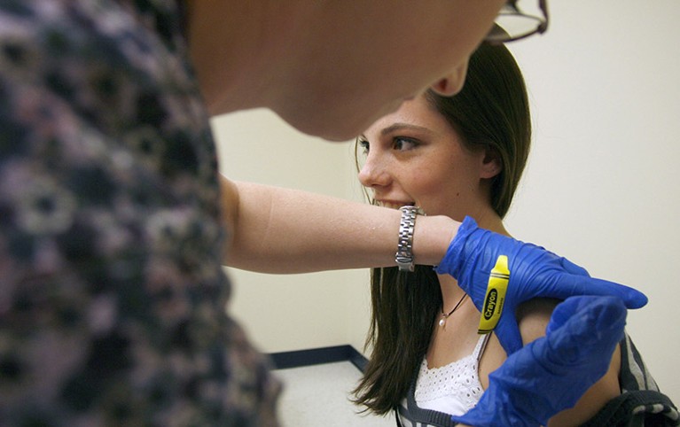 A girl receives an HPV vaccine shot from medical assistant.