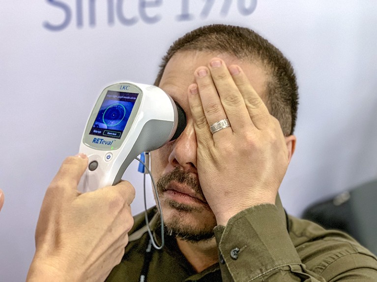 A patient has his retinal response measured with a hand-held machine for electroretinography