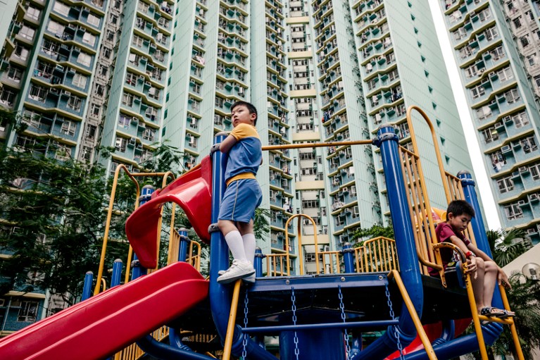Children play in a small park at the base of a highrise residential block in Hong Kong