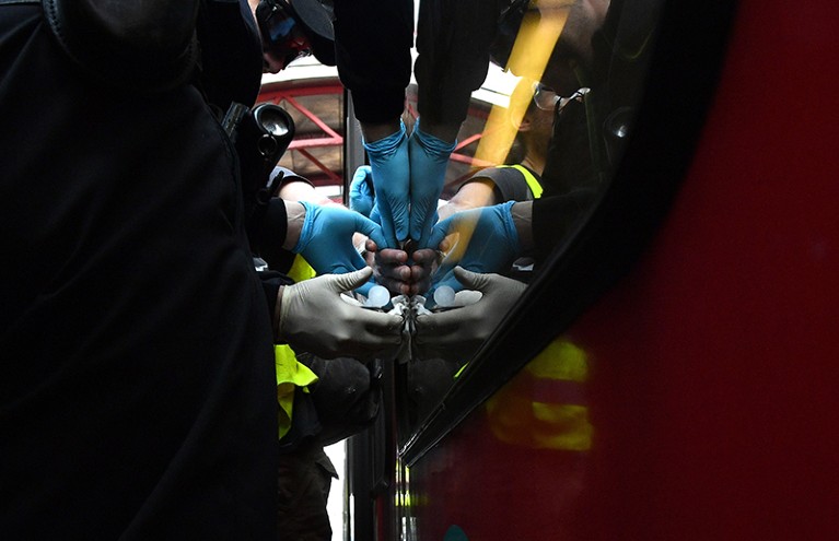 Police officers work to remove the hand of a protester who has super-glued their hand to a train window