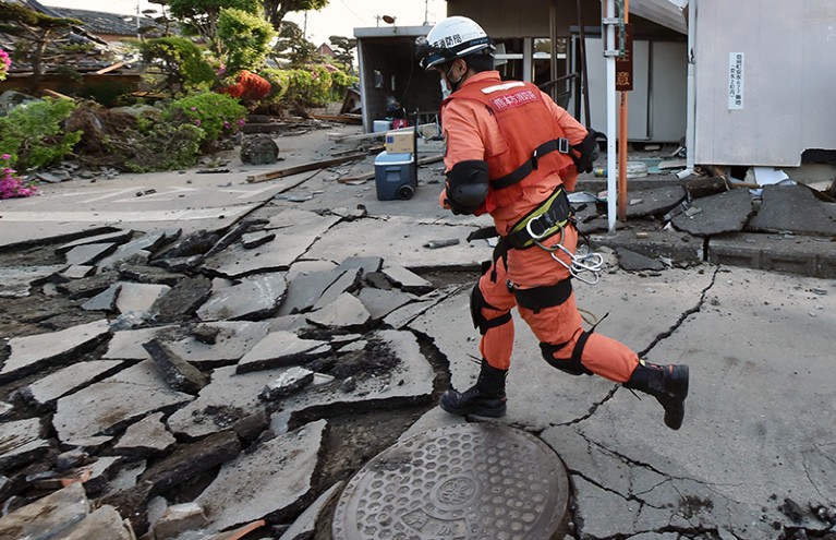 A member of a rescue team runs on a street cracked by an earthquake in Mashiki, Japan