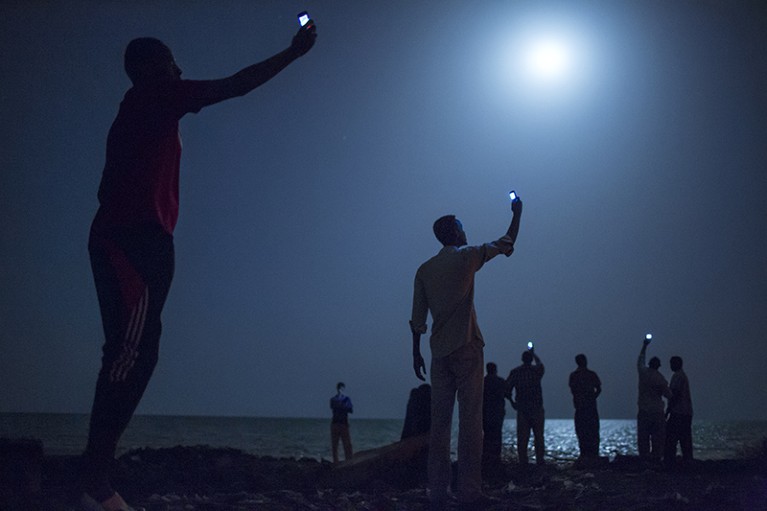 African migrants hold cell phones.