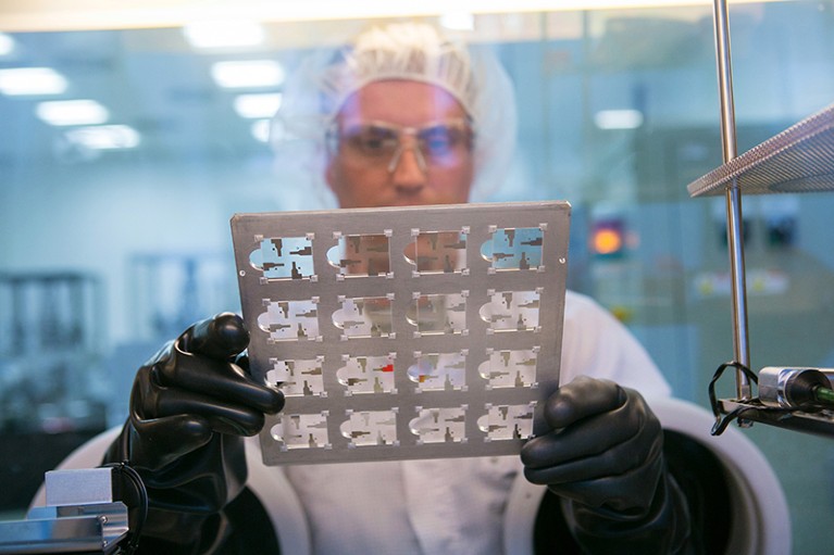 A technician holds a sheet of pre-coated OLED test cells in a laboratory