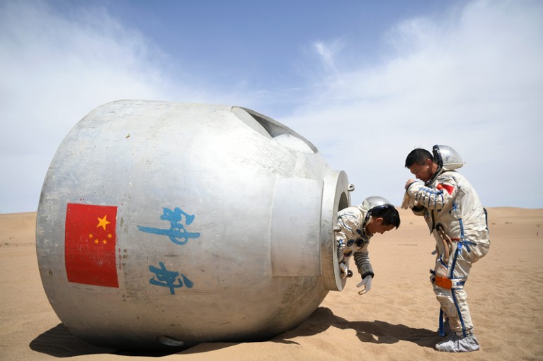 Chinese astronauts Nie Haisheng and Liu Wang exit from a re-entry capsule during a wilderness survival training in China