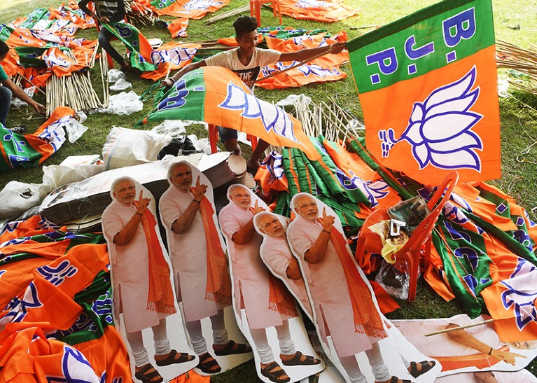 Indian labourers arrange Bharatiya Janata Party (BJP) flags and cut-outs of Indian Prime Minister Narendra Modi
