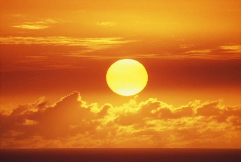 A huge orange sun sinking towards the horizon