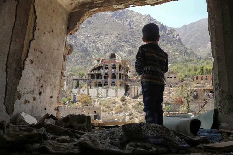 A Yemeni child looking out at buildings that were damaged in an air strike in the southern Yemeni city of Taez.