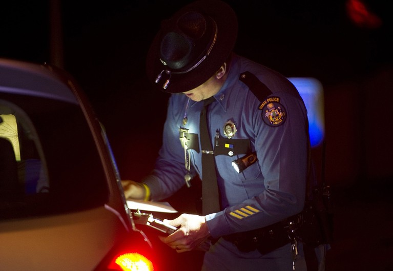 A State Police Trooper talks with a driver after pulling him over for speeding