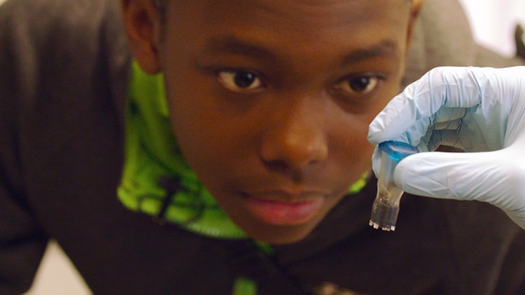 A teenager with sickle-cell disease looks at a tube containing the CRISPR gene editing machinery