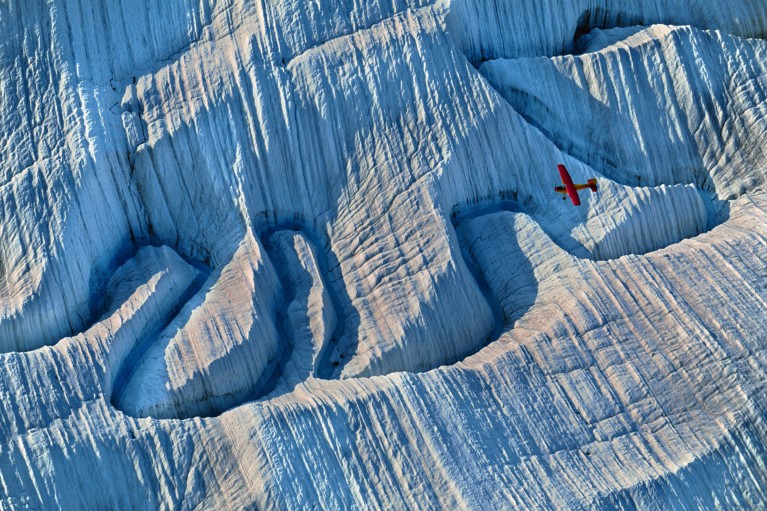 A plane flying over a river of meltwater on glacier in Alaska