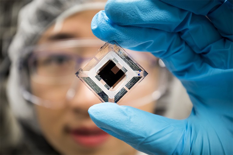 photo of Xiaozhou Che, EECS Graduate Research Assistant, holding an organic tandem photovoltaic cell.