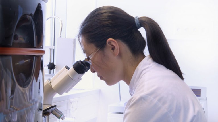 Scientist using microscope in lab.