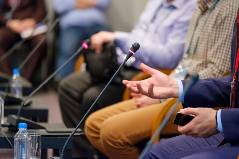 Men speak on a panel at a conference