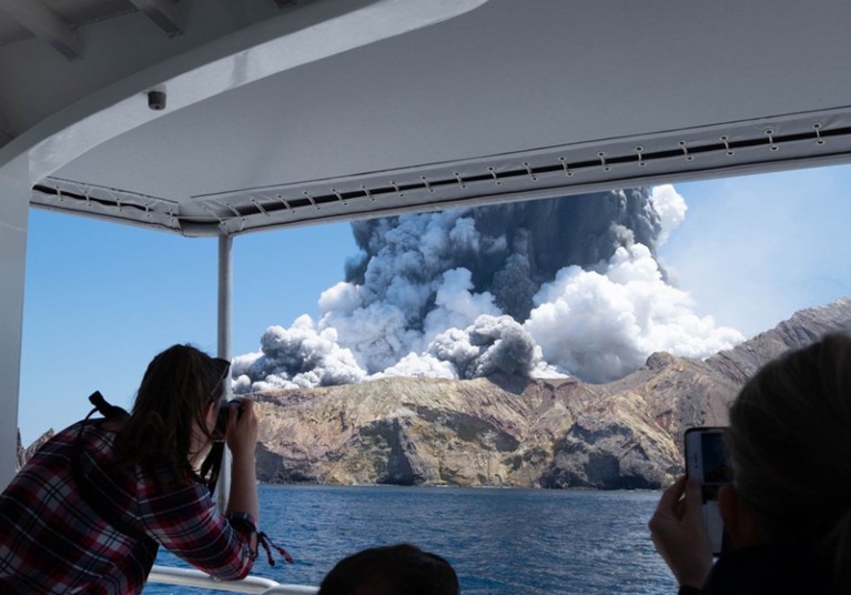 A person takes photos of volcanic eruption at New Zealand's White Island