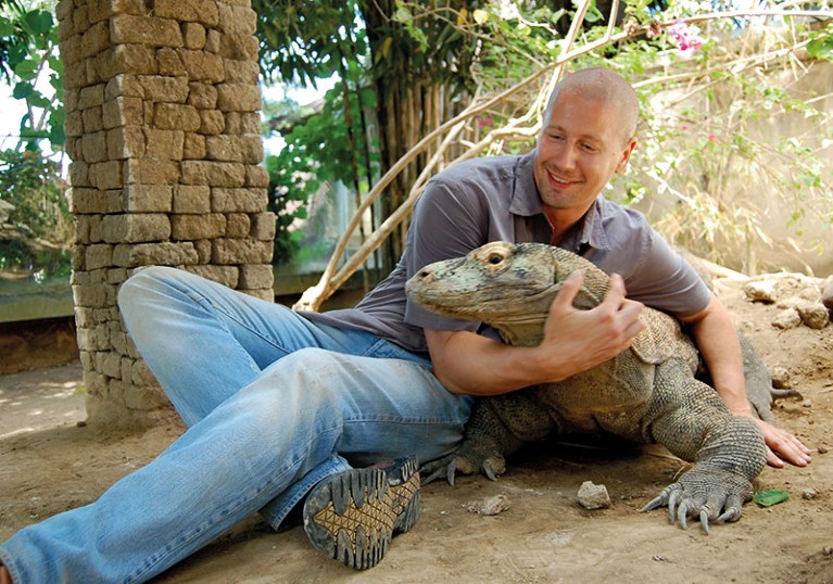 Bryan Fry sits on the ground with a Komodo dragon