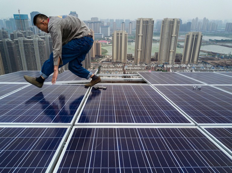 A Chinese worker installing solar panels on the roof of a 47 story building in Wuhan, China