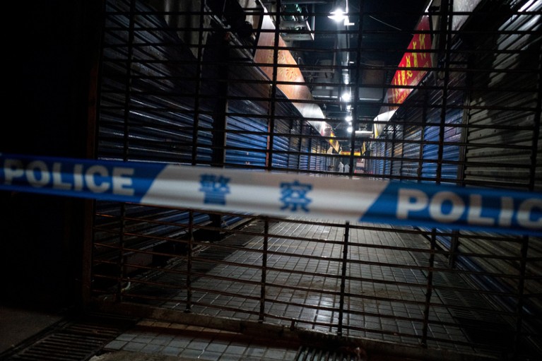 Wuhan Hygiene Emergency Response workers, seen behind a police cordon, conduct searches on the Huanan Seafood Wholesale Market