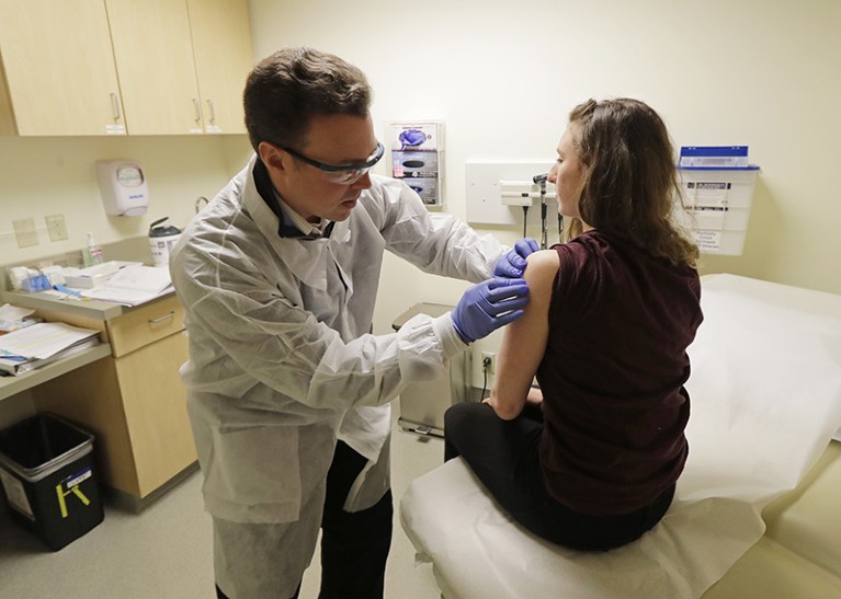 A pharmacist gives a shot to a woman in the first-stage safety study clinical trial of a potential vaccine for the coronavirus
