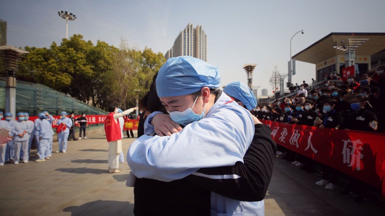 A medical worker (R) embraces a member of a medical assistance team from Jiangsu province.