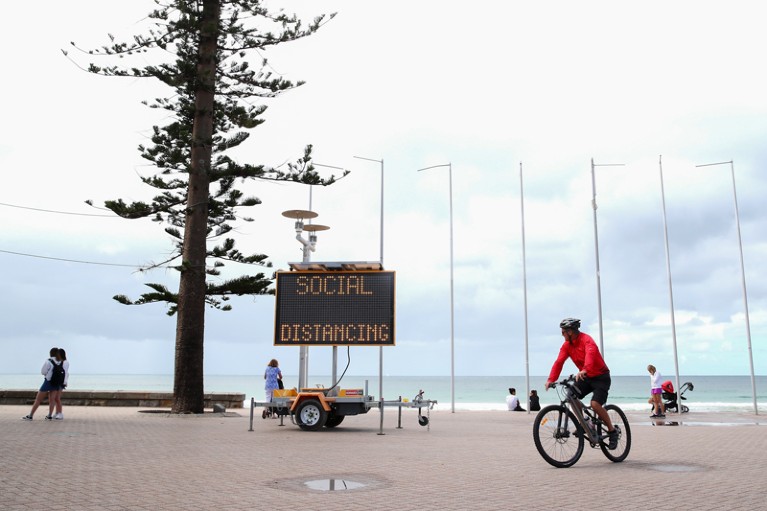 A sign reading 'social distancing' is displayed at Manly Beach