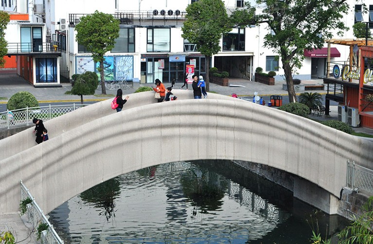 People walk on the 3D-printed concrete pedestrian bridge developed by Tsinghua University (School of Architecture)
