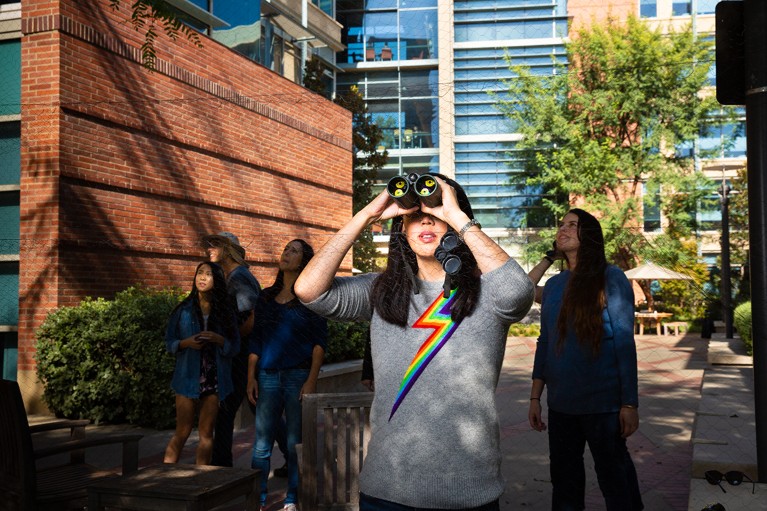 Pamela Yeh looks through binoculars as she & her students study dark-eyed juncos on the UCLA campus