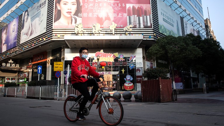 A man wears a protective mask as he ride a bike in the business street on February 13, 2020 in Wuhan.