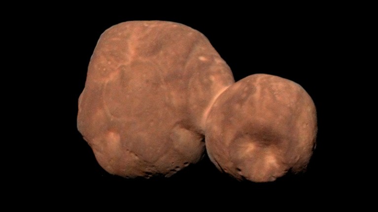 A red rocky object made of two loosely connected lobes, against a black background.