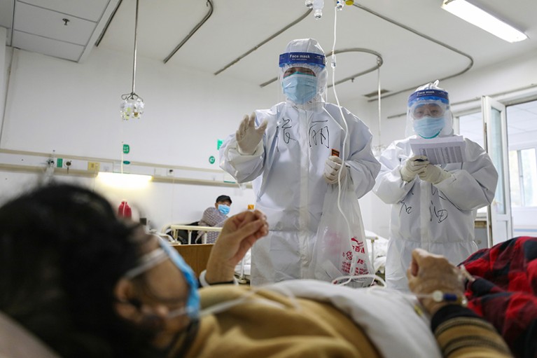 Two medical personnel check on the conditions of a patient with COVID-19 in Jinyintan Hospital