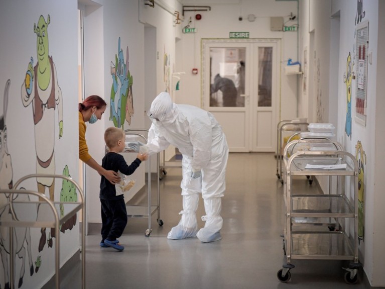 A child infected with COVID-19 is comforted by a medical personnel at a hospital in Romania.