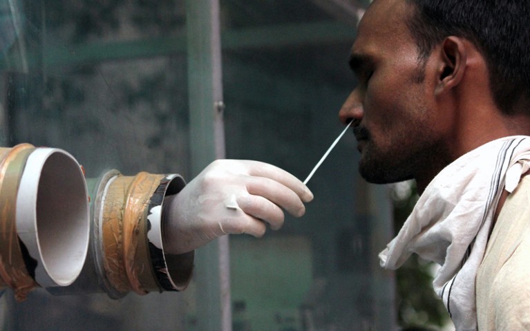 A health worker collects a nasal swab sample from people during weekly market for Covid-19 Rapid Antigen Testing.
