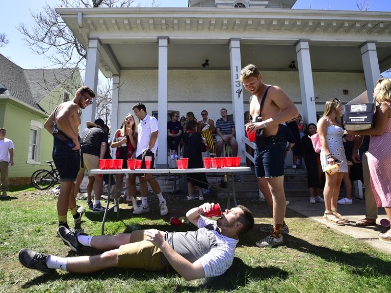 A University of Colorado Boulder student chugs a beer at a graduation party outside of a home, US.