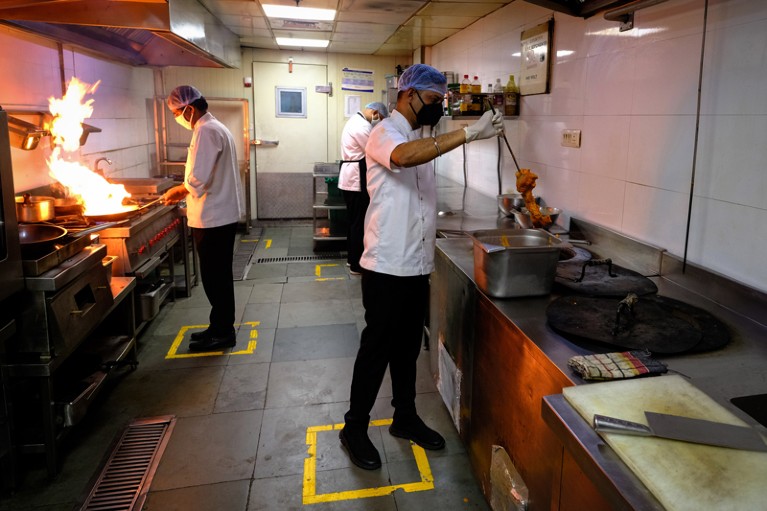 Chefs prepare food as they stand in boxes marked out to assist social distancing