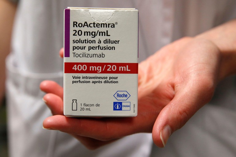 A pharmacist displays a box of tocilizumab