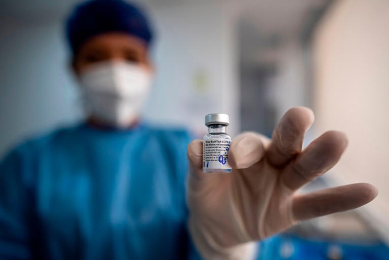 A health worker holds a vial of the Pfizer-BioNTech vaccine