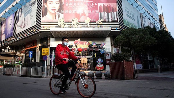A man wears a protective mask as he rides a bicycle down a deserted street in Wuhan