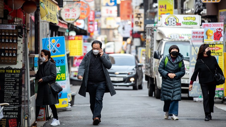Pedestrians wearing protective masks walk past stores in the Jongno district of Seoul, South Korea.