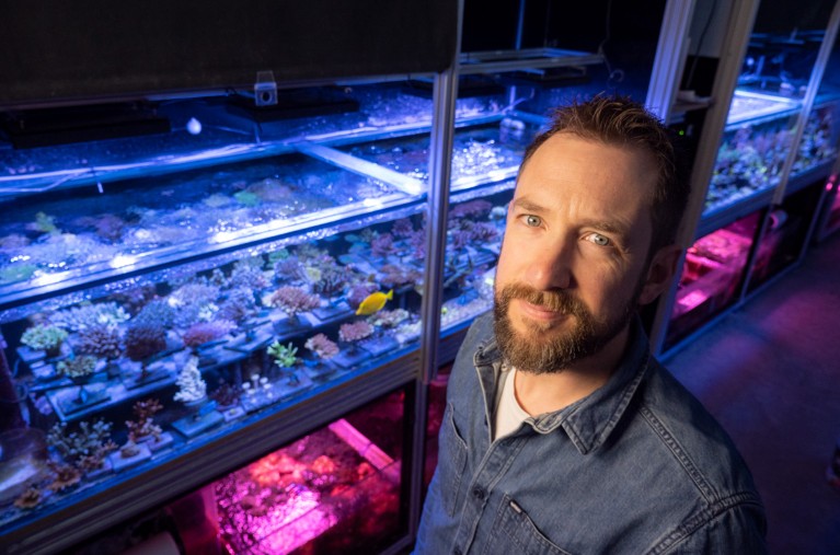 Jamie Craggs stands in front of the aquarium in which he grows coral