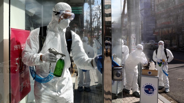 A group of people wearing protective gear and carrying spray bottles.