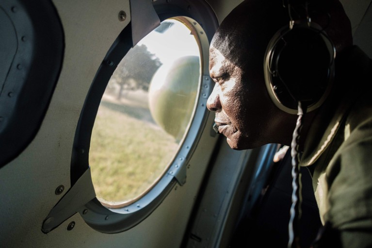 A member of the Uganda Peoples Defence Force looks out the window of a military helicopter as is tracks a locust swarm