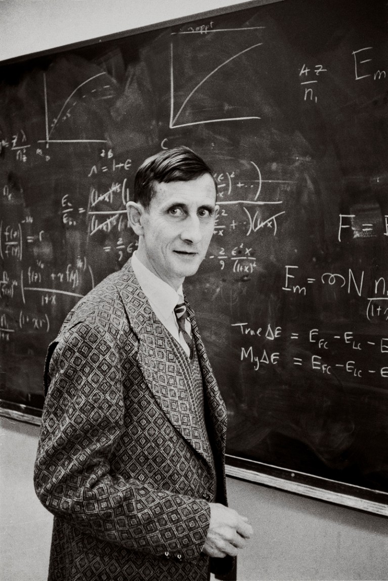 Portrait of Freeman Dyson standing at a chalk board with equations and charts in 1972