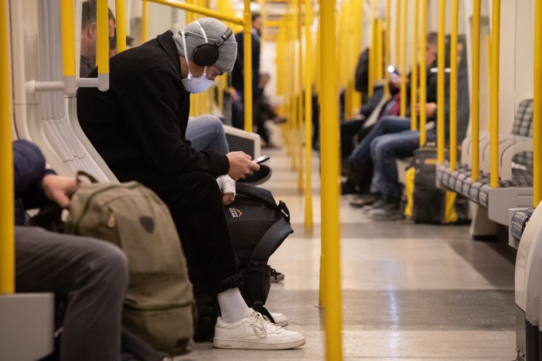Commuters wearing face masks sit on a half-empty London Underground train